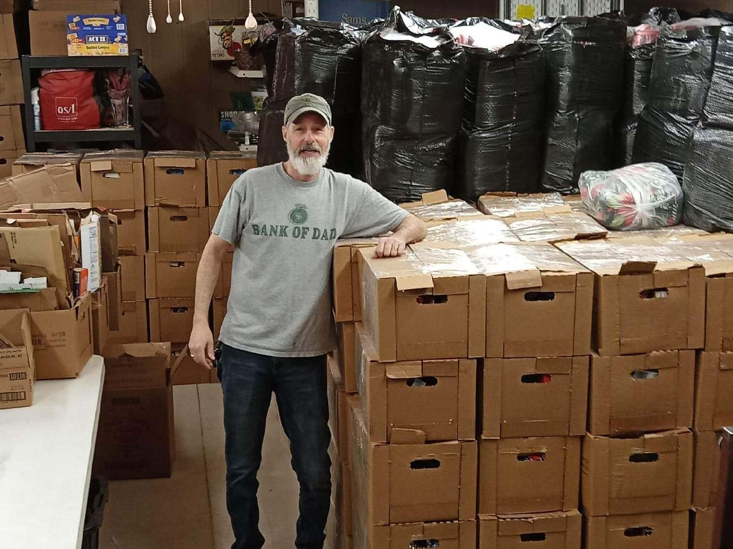 Packs for Hunger volunteer standing with the boxes of food